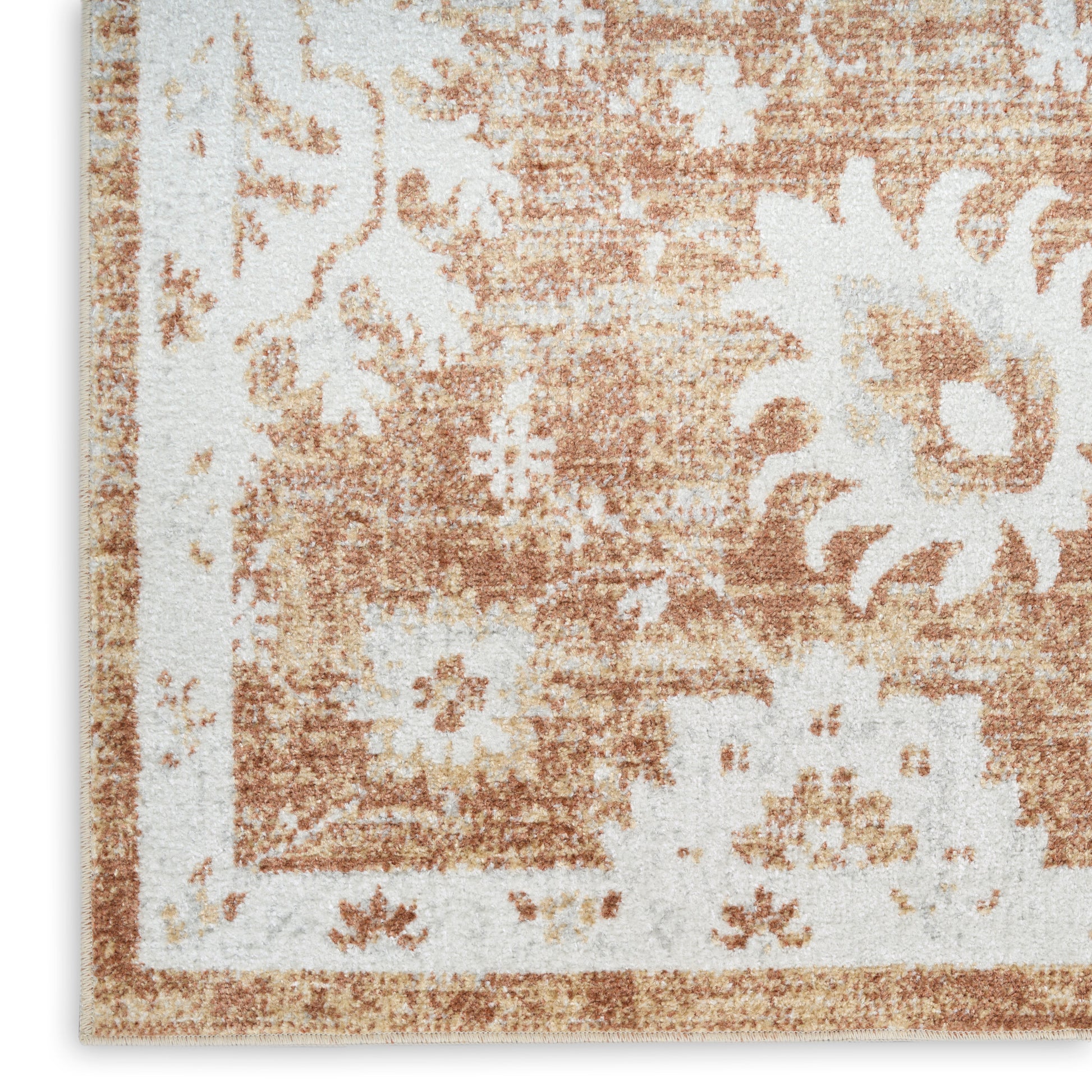 Close-up of a distressed vintage floral rug with beige and tan tones and a bordered corner.