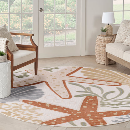 Round coastal outdoor rug with orange starfish motifs and neutral palm leaf accents in a sunlit outdoor setting.