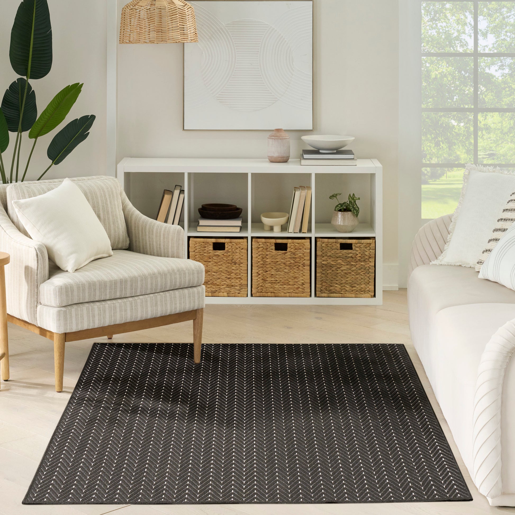 Neutral living room with beige upholstered armchair, white sofa, black rug, cubby storage with wicker baskets.