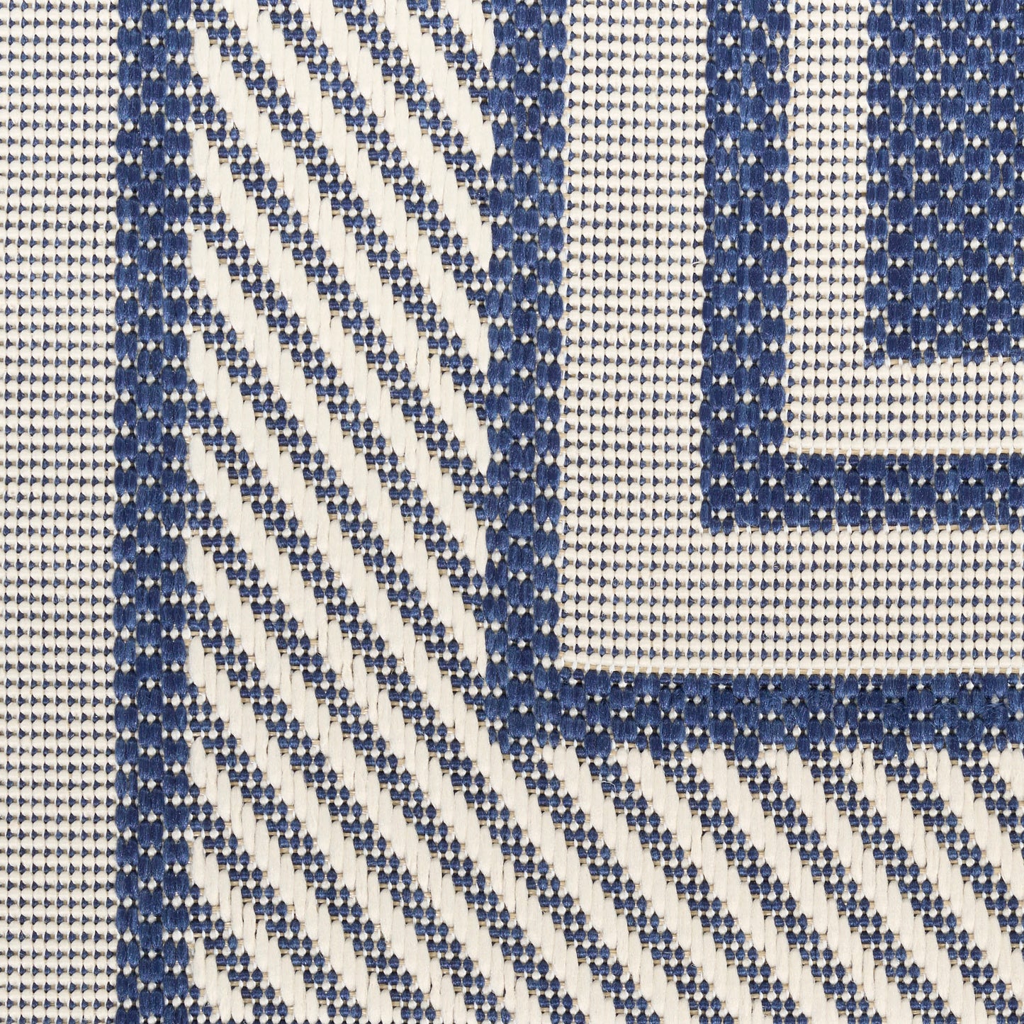 Close-up of navy blue & white woven rug with diagonal chevrons & a bordered square frame.