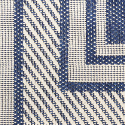 Close-up of navy blue & white woven rug with diagonal chevrons & a bordered square frame.