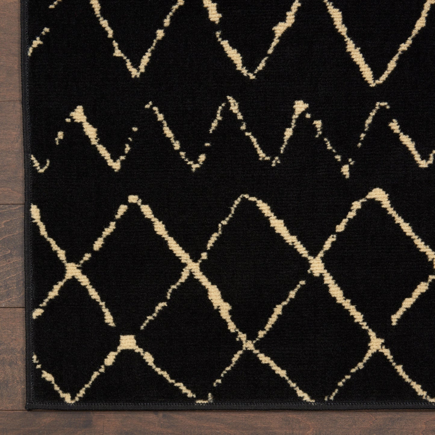 Rectangular black rug with cream geometric diamond lattice, beige lines, bordered in black; modern living room accent.
