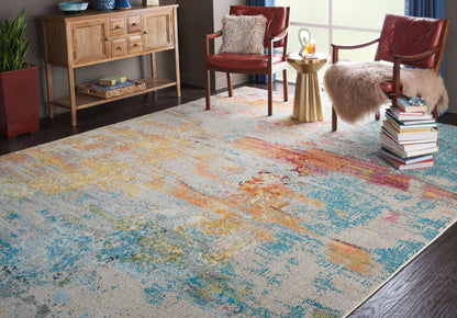 Colorful abstract area rug with blue, orange, and yellow patches in a cozy living room with red chairs, fur throws, books.