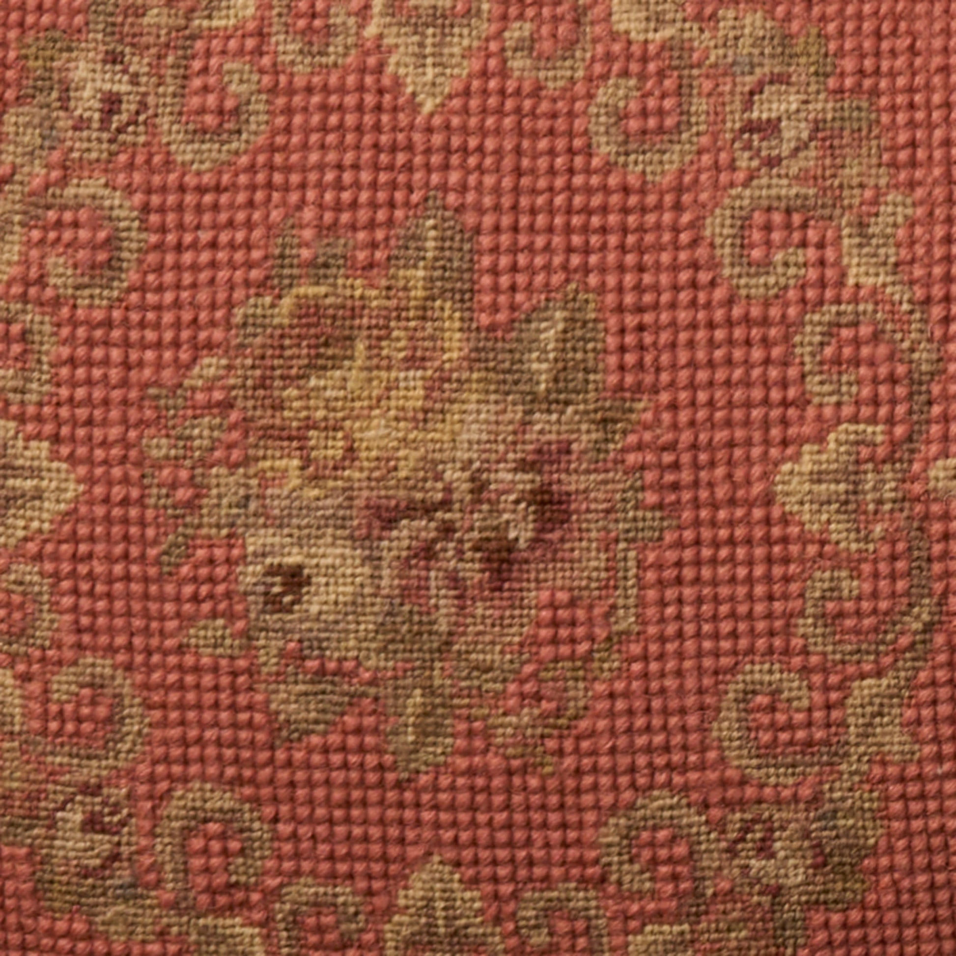 Red woven rug with gold floral medallion and scrolling border; textured textile.