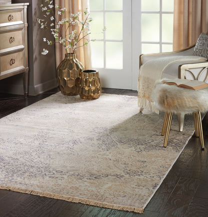 Beige damask area rug with fringe, gold hammered metal vases, fur stool with gold legs in a sunny living room.