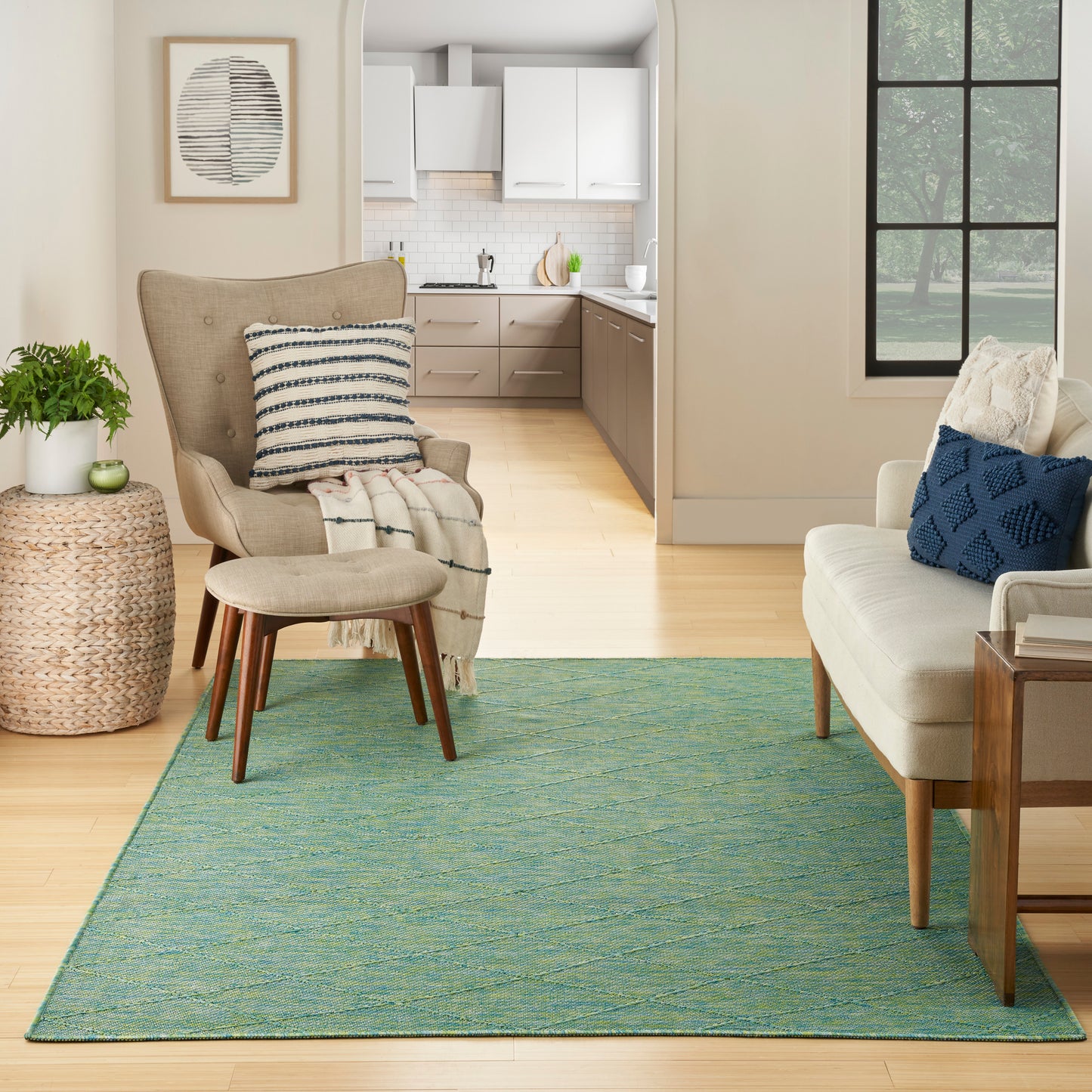 Teal woven area rug in a cozy living room with beige armchair, striped pillow, woven side table, and cream sofa with blue cushion.