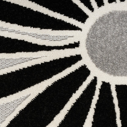 Shaggy sunburst rug in black and cream with a gray circular center; plush, geometric statement floor decor.
