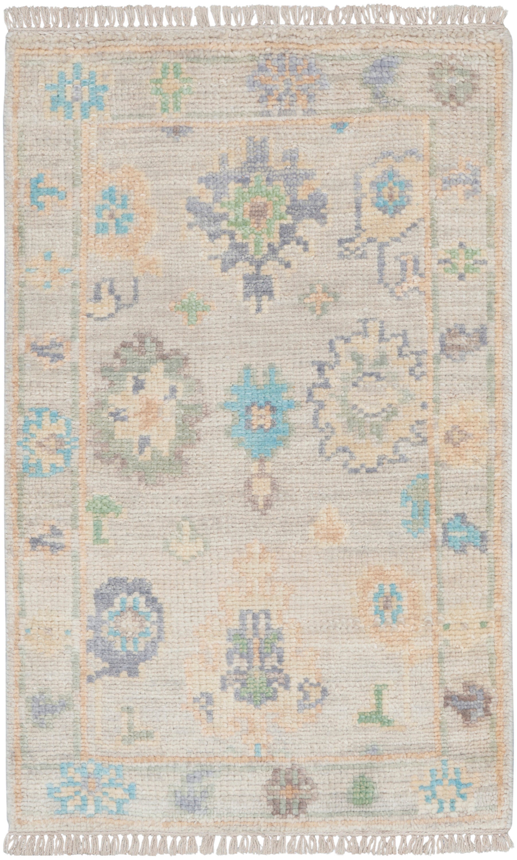 Pastel floral rug with beige base, blue, mint, and peach motifs; fringed ends and decorative border.