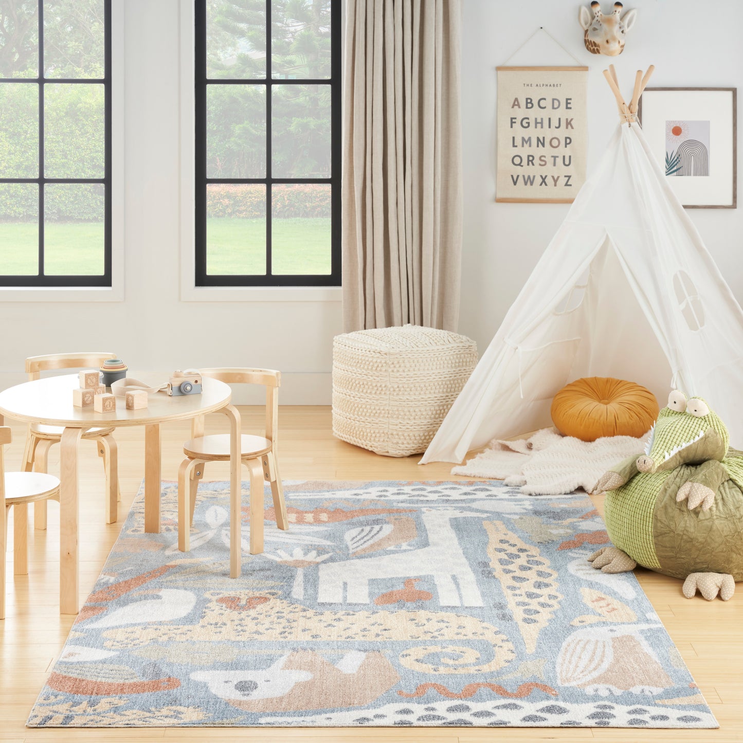 Bright kids' playroom with white teepee, blue patterned rug, wooden table and chairs, woven pouf; cozy Scandinavian style.