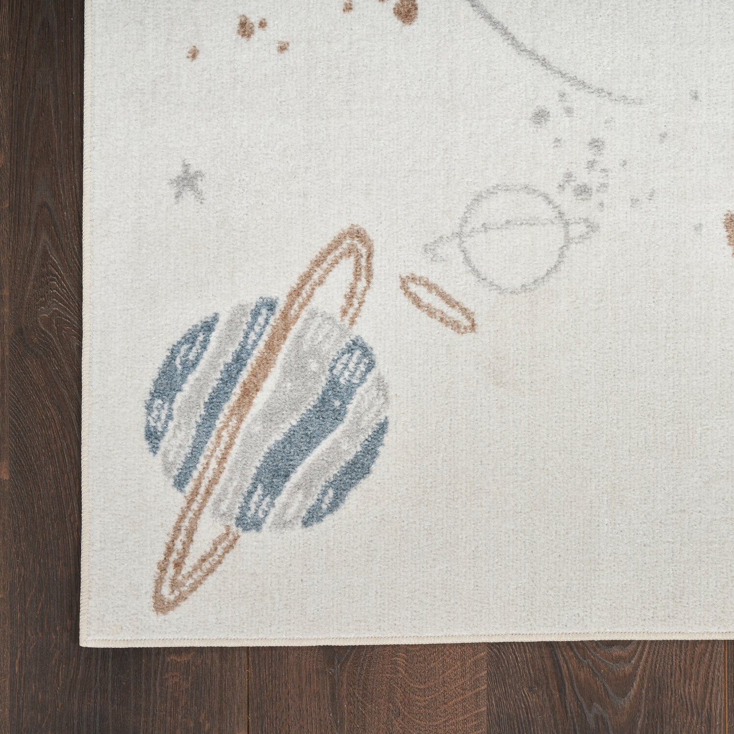 Beige rug with space motif: Saturn-like blue planet with brown rings and small stars.