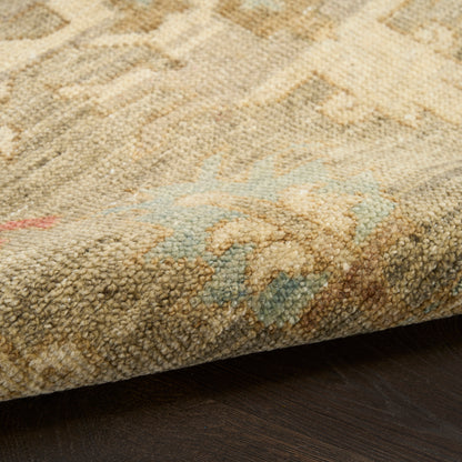 Close-up of a tufted beige oriental rug with pale blue accents and a folded edge on dark wood floor