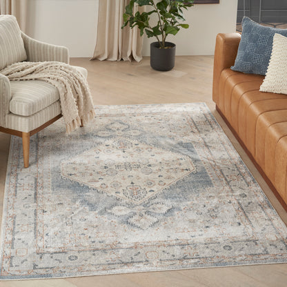 Vintage blue-gray and ivory oriental rug on light wood floor, flanked by beige armchair and caramel leather sofa.