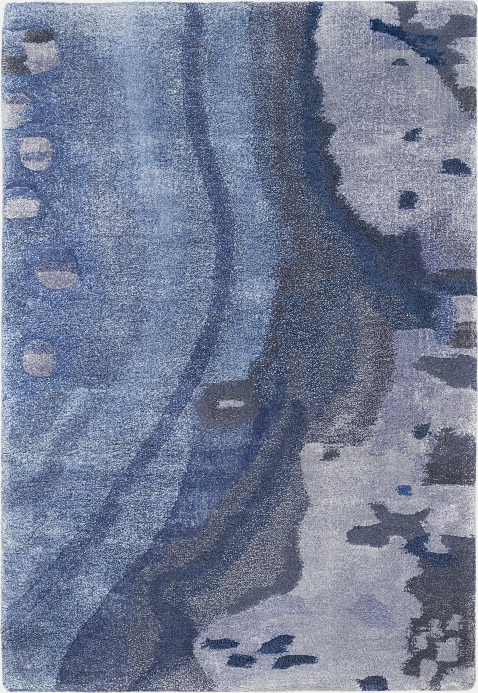 Blue abstract area rug with flowing curves, navy and light blue shades, and irregular gray-blue spots.