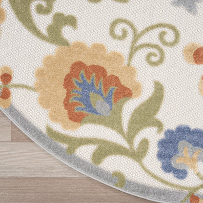 Curved-edge floral area rug on wood floor; beige background with peach, blue and orange flowers, green vines and gray border.