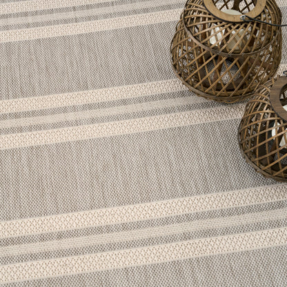 Two round brown wicker lanterns on a gray striped rug for cozy rustic decor.