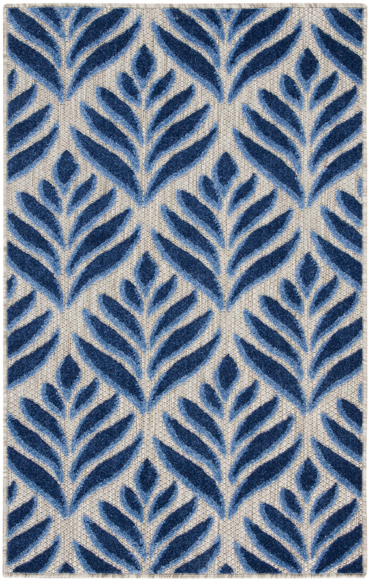 Rectangular tufted rug with navy blue fern-like leaf motifs on a beige woven ground; modern botanical decor for living room.