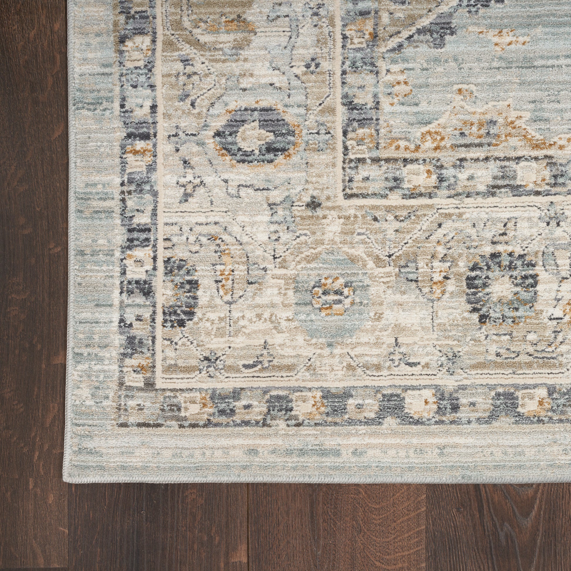 Rectangular distressed blue, ivory, and beige oriental runner with an ornate border on dark wood floor.