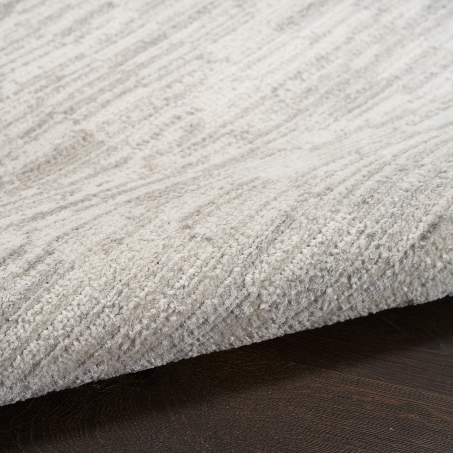 Rectangular light-gray plush runner with textured pile on dark wood floor