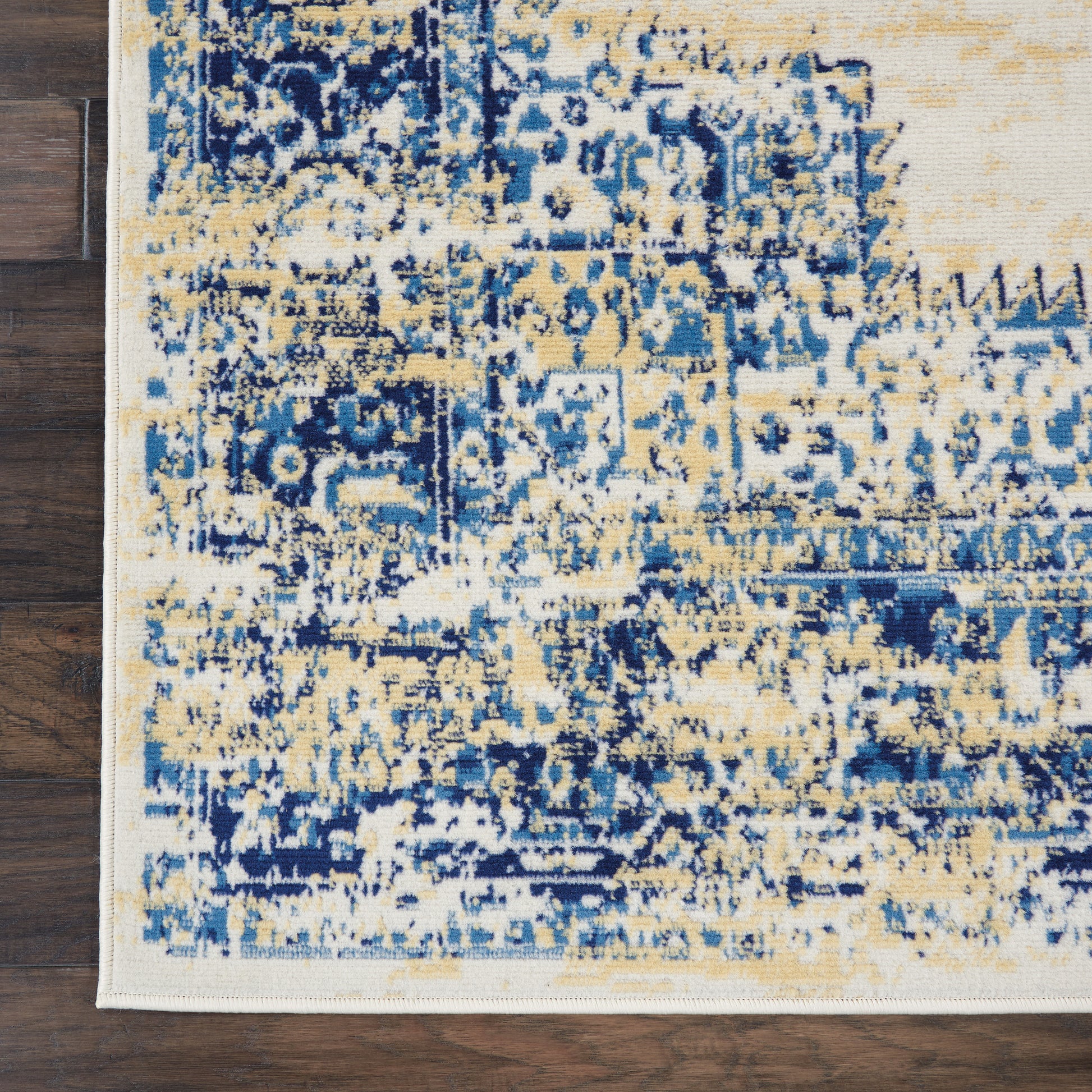 Abstract distressed area rug in blue and beige tones with cream border, rectangular, on hardwood floor