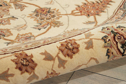 Cream oriental rug with brown, gold, and red floral pattern; curled edge on light wood floor.