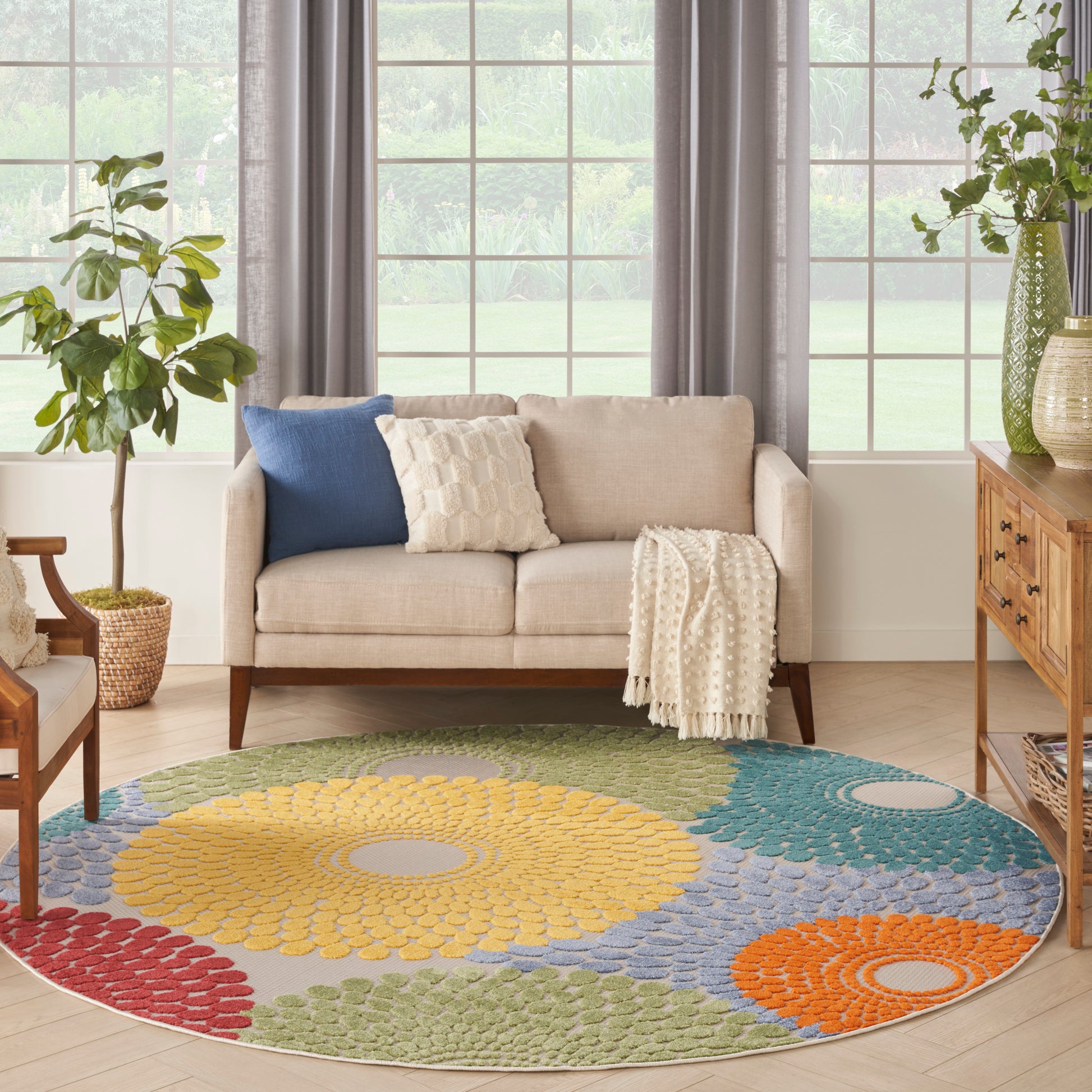 Round multicolor rug with yellow, blue, green and orange circles under a beige sofa with blue and cream cushions.