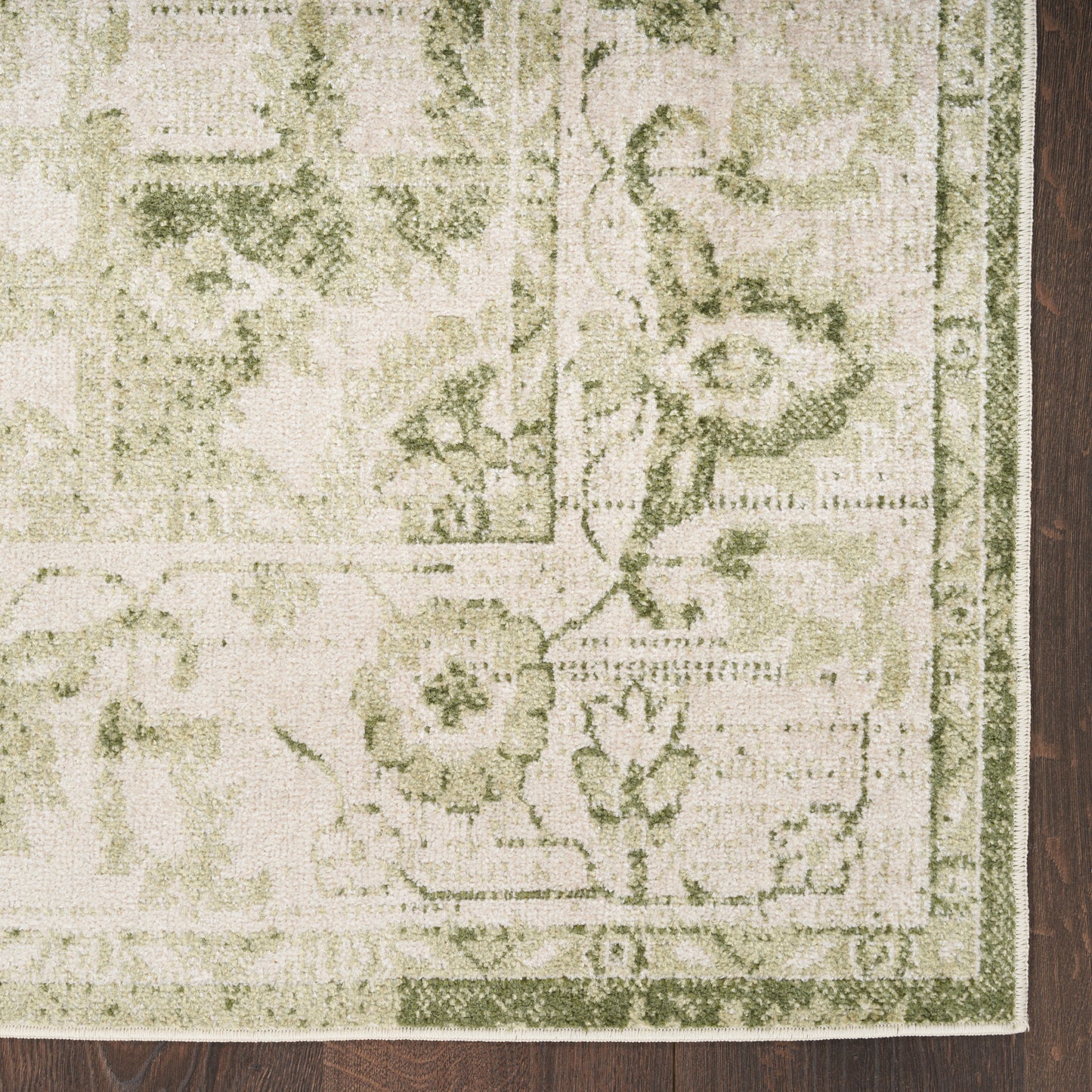 Beige and sage green floral area rug with decorative border, rectangular, on dark wood floor.