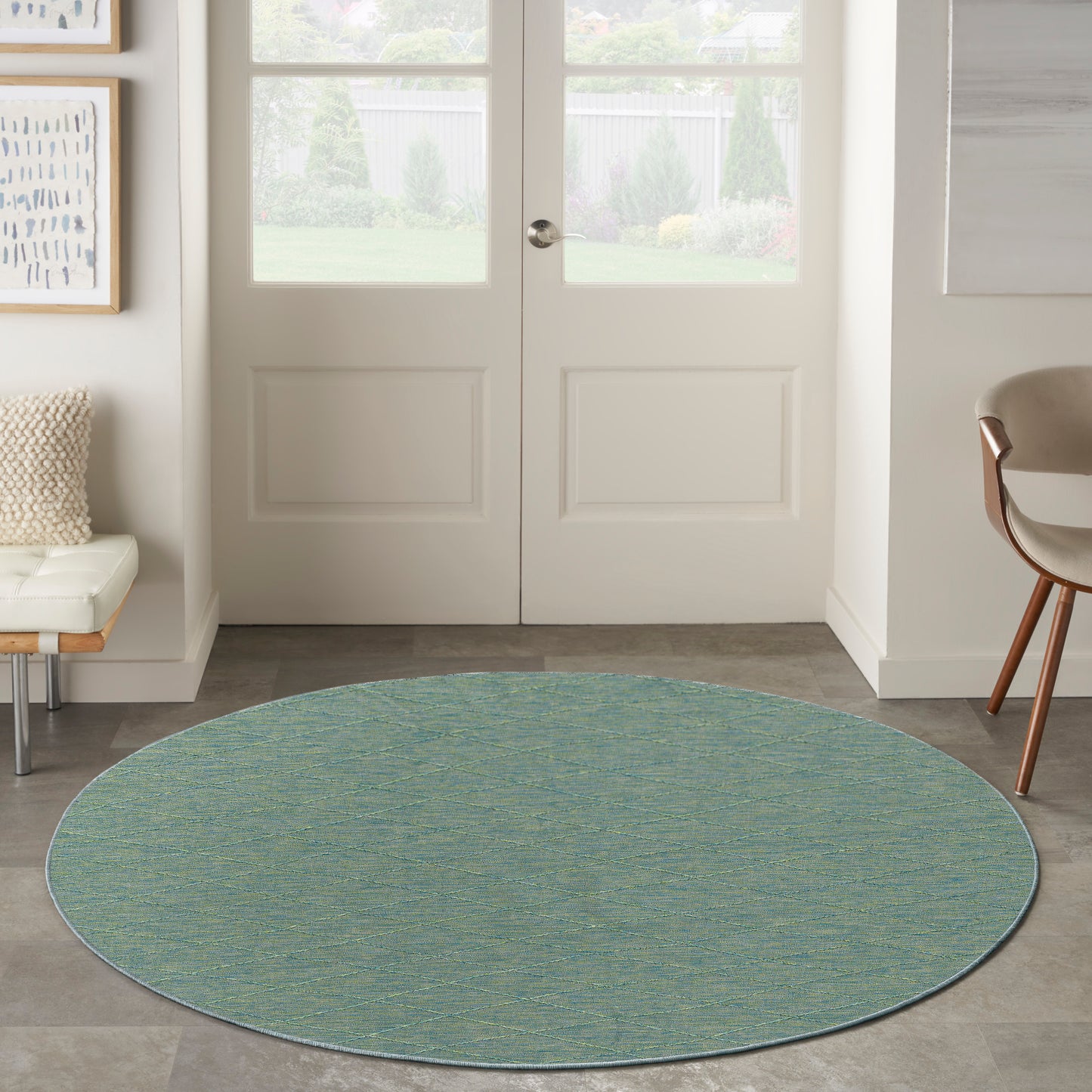 Round teal-green textured area rug in a bright entryway with double doors and modern seating.