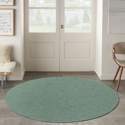 Round teal-green textured area rug in a bright entryway with double doors and modern seating.