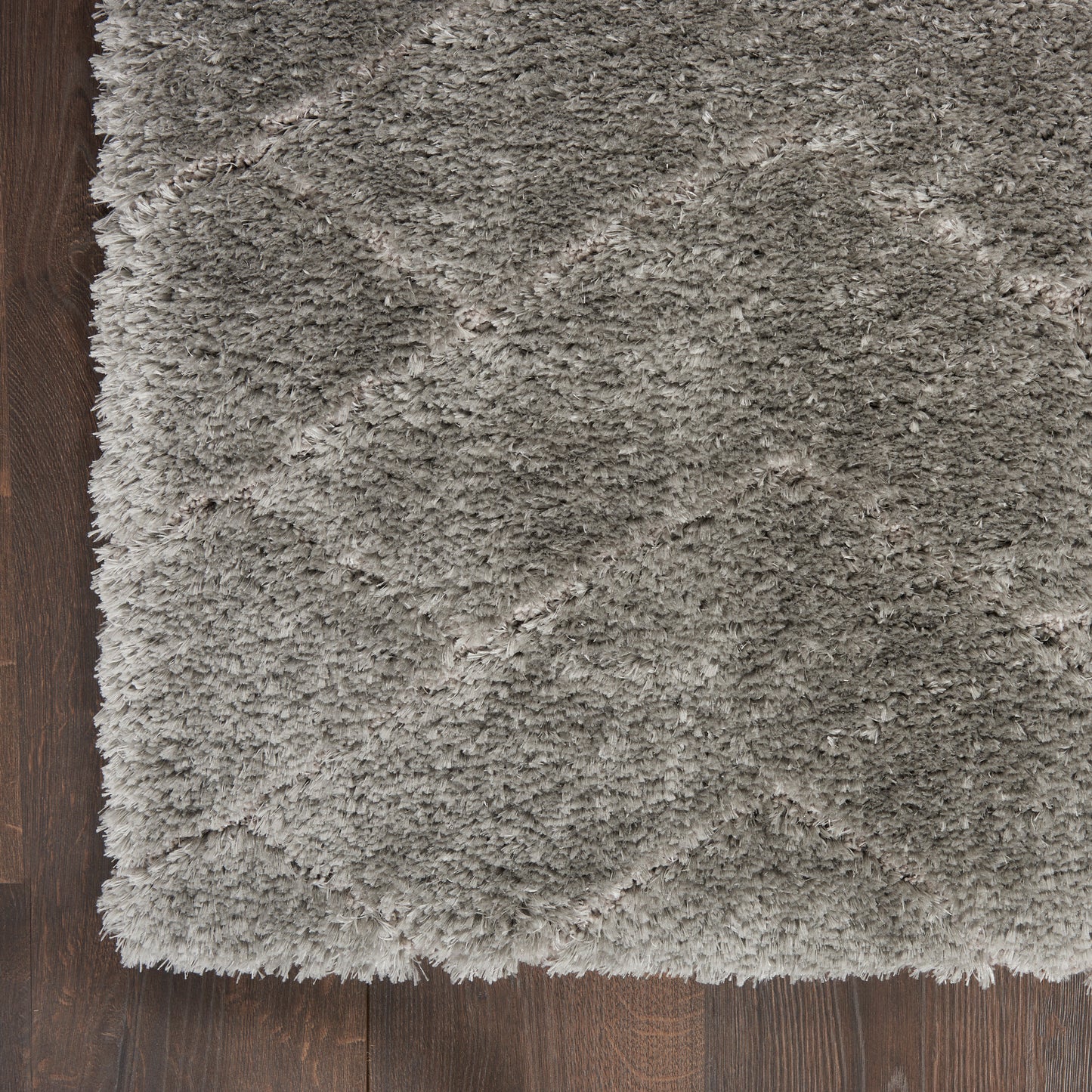 Gray shag rug with long plush pile on dark wood floor; corner edge visible.