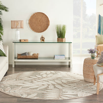 Coastal living room with glass-top white console, woven wall art, potted grasses, wicker baskets, and beige leaf-pattern rug