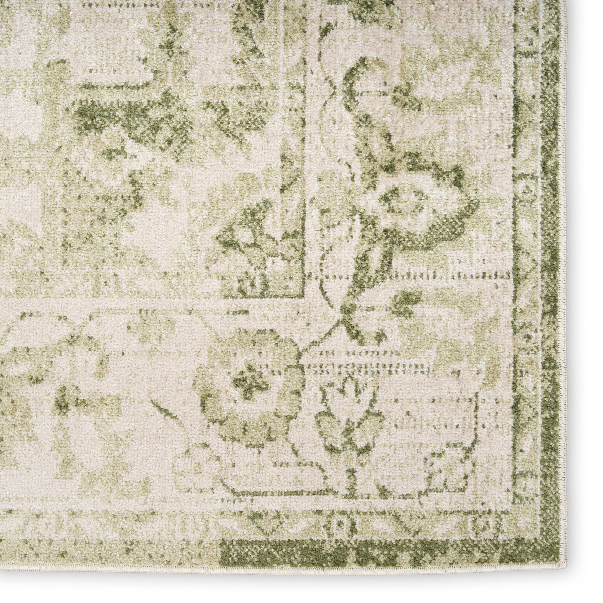 Beige and sage green vintage-style rug close-up with floral pattern and decorative border.
