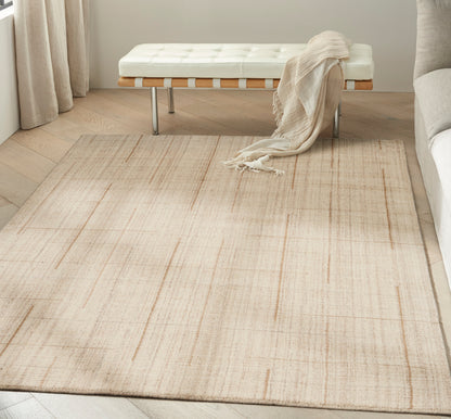 Beige flat-weave area rug with a subtle linear pattern in a modern living room with a white tufted bench and cream throw.