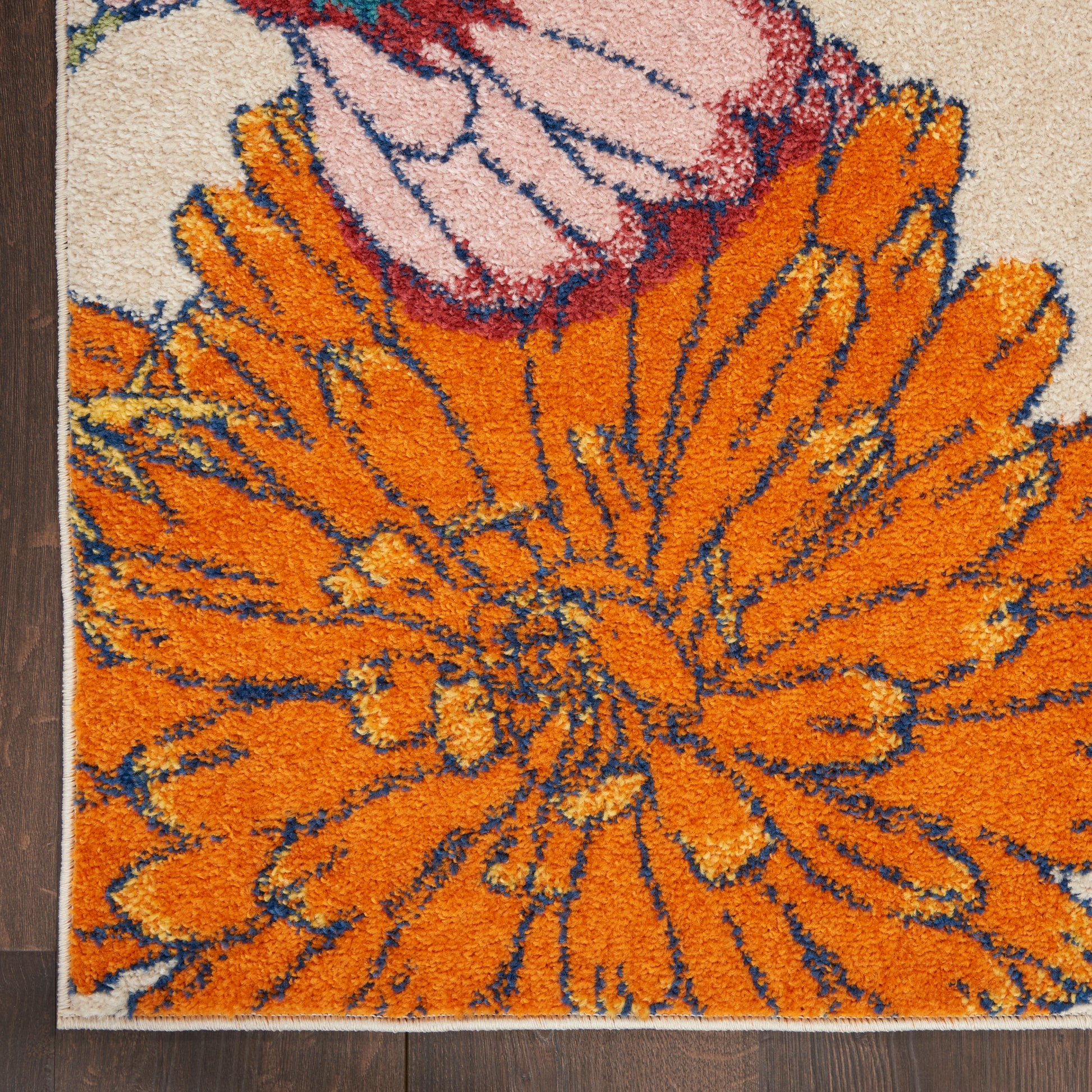 Bright orange floral rug with large petals on beige background; blue outlines, tufted texture on wood floor.