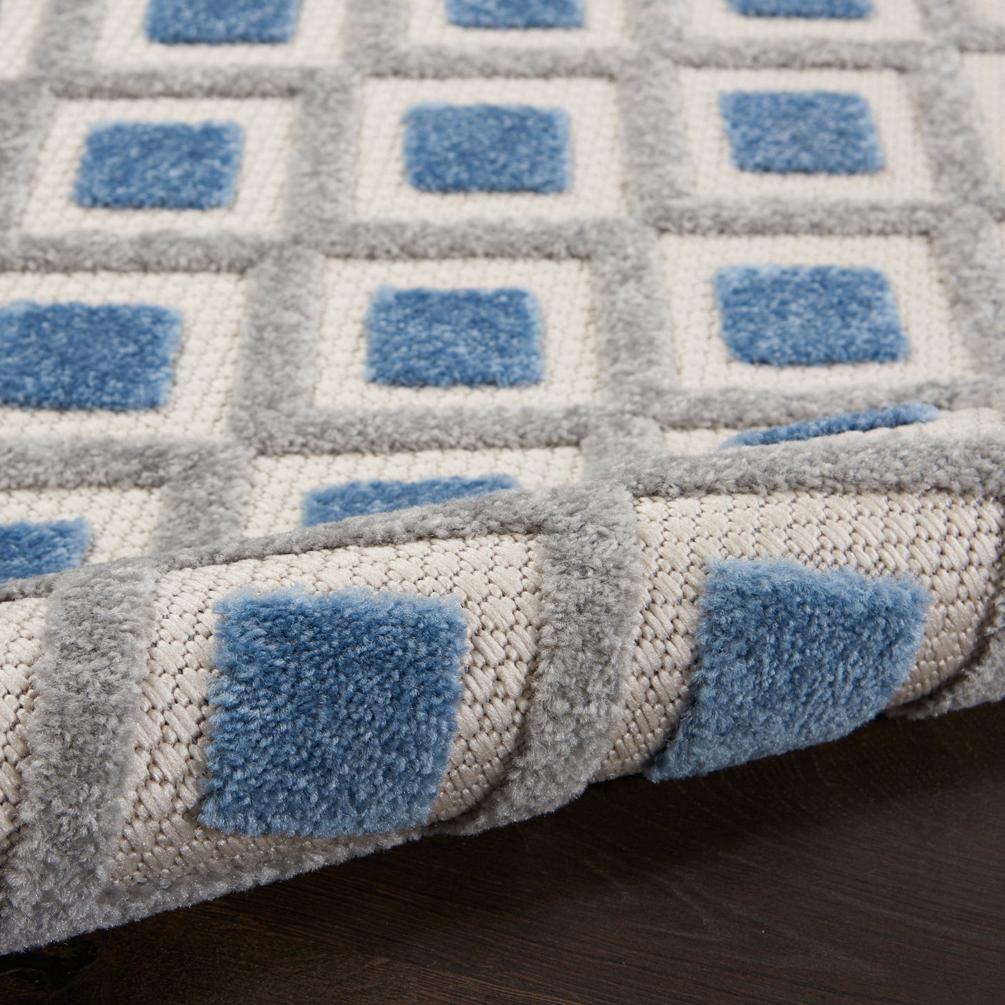 Soft tufted area rug with blue squares in a light gray grid; plush pile, rolled edge, modern geometric.