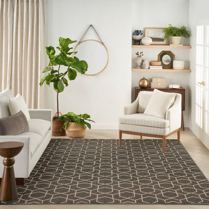 Neutral living room with beige sofa, striped armchair, geometric rug, potted plants, and round wood wall hoop.