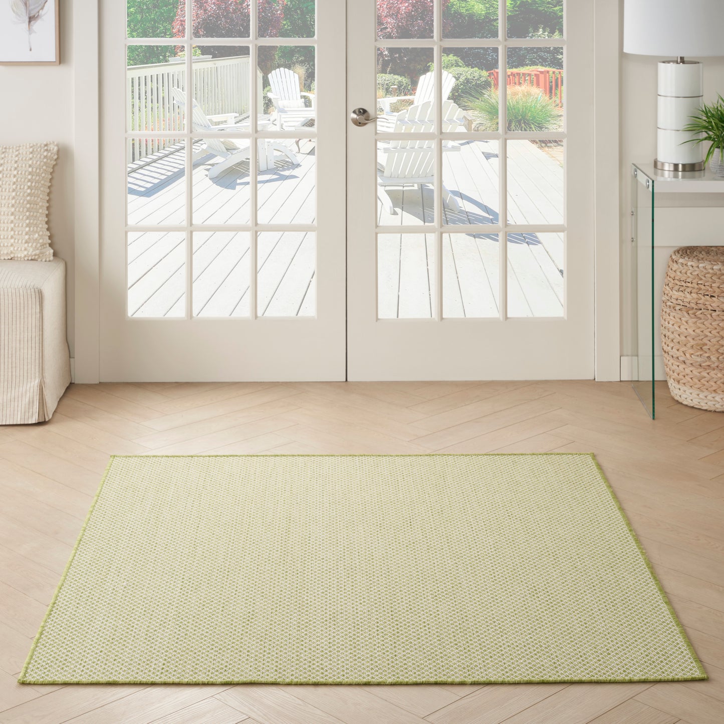 Rectangular light olive-green area rug with lime border in a bright living room by glass doors.