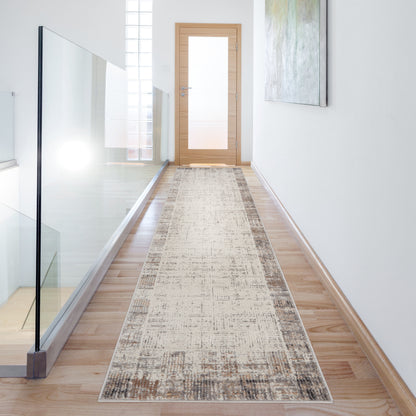 Beige patterned hallway runner rug on light wood floor, glass railing on the left, wooden door at the end, abstract wall art on the right.