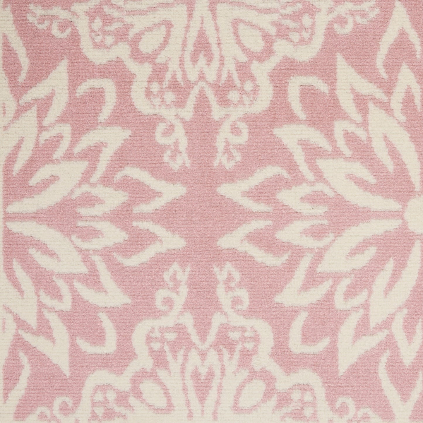 Soft pink rug with ivory damask floral pattern; ornate, symmetrical baroque-style motif.
