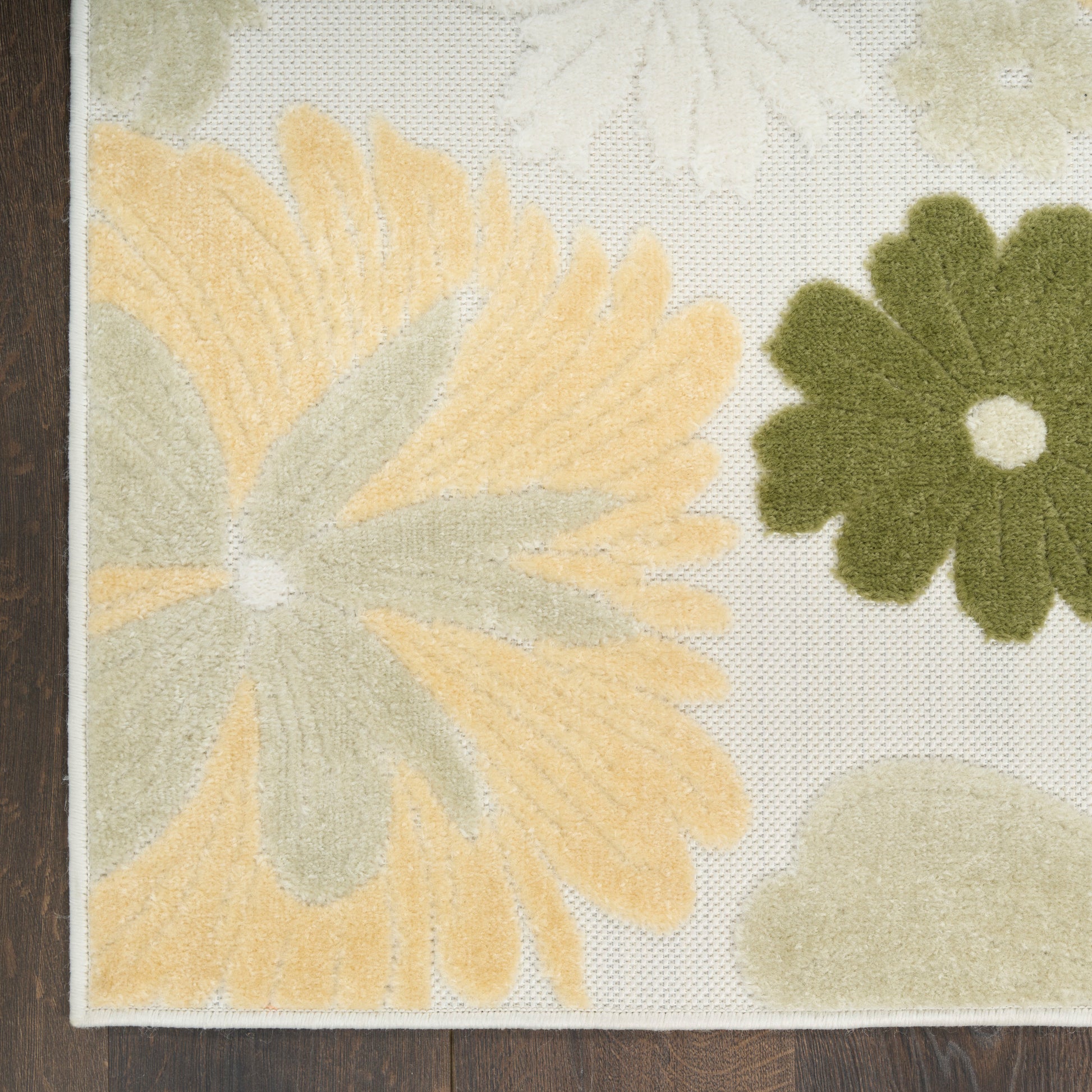Cream floral area rug with oversized yellow & green petals, tufted soft pile, bordered edge on dark wood floor.
