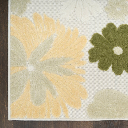 Cream floral area rug with oversized yellow & green petals, tufted soft pile, bordered edge on dark wood floor.