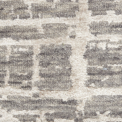Neutral gray and beige rug with a thick plush pile and distressed geometric brick-pattern design.