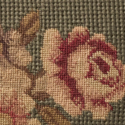 Close-up of a woven floral design: pink rose with beige petals, brown stems, on a muted gray-green background.
