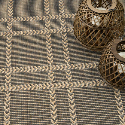 Geometric beige chevron rug in dark gray, paired with brown woven rattan lanterns.