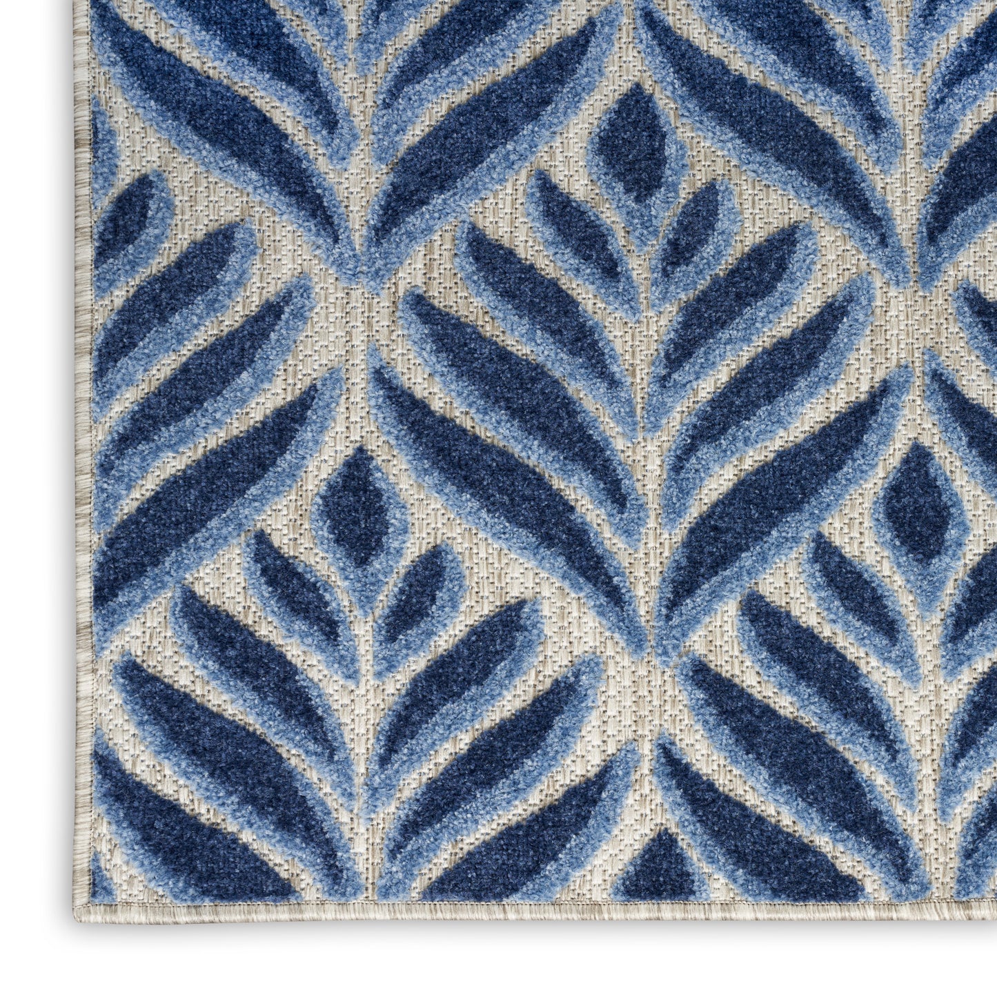 Close-up of a beige woven rug with repeating navy blue leaf-patterned botanical motifs.