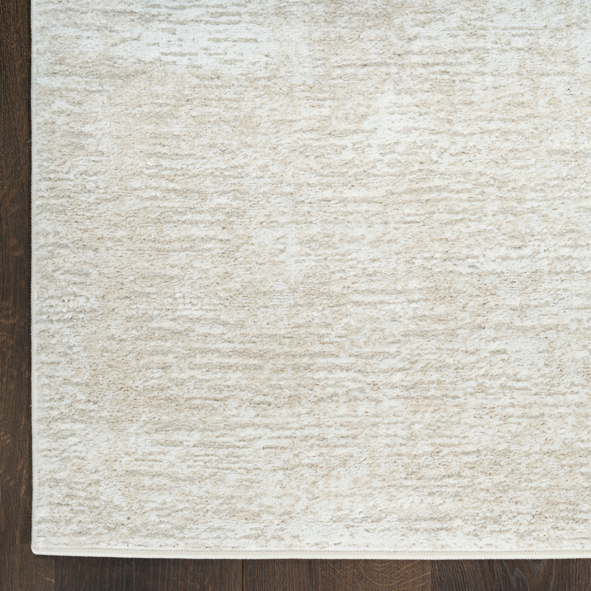 Cream textured area rug with plush pile on dark wood floor; rectangular, neutral-toned.