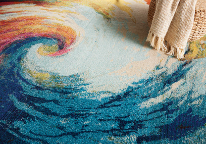 Colorful abstract swirl rug in blues, teals, pinks and yellows with fringe along the edge.