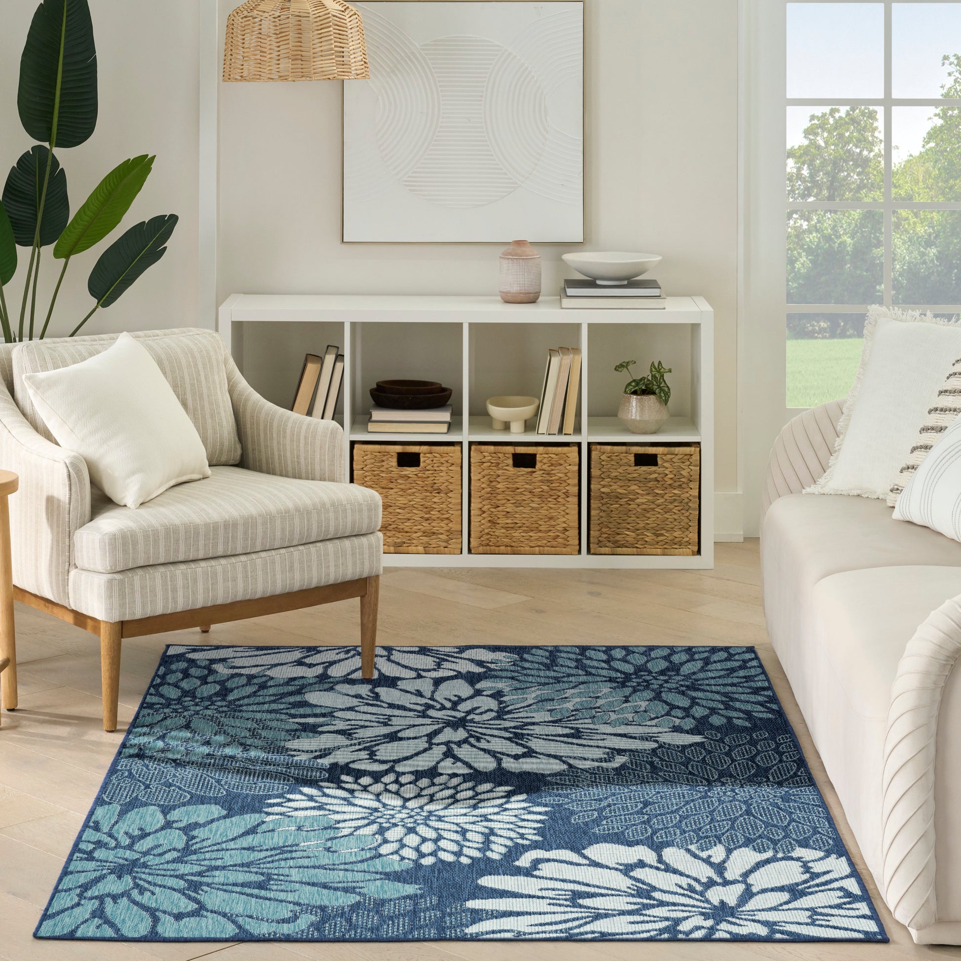 Blue floral area rug in a bright living room with white furniture, woven baskets, and a white cubby shelf.