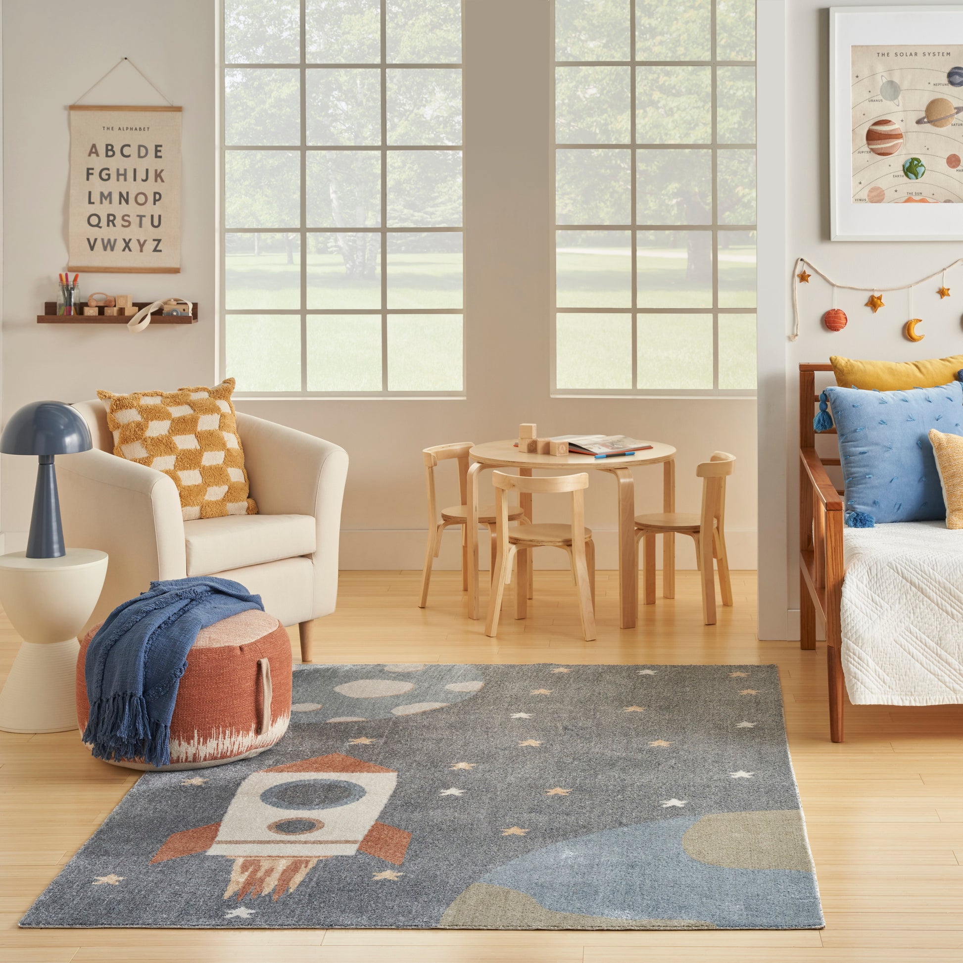 Cozy kid's room with light wood furniture, alphabet poster, round table, cream chair, space-themed rug and blue accents.