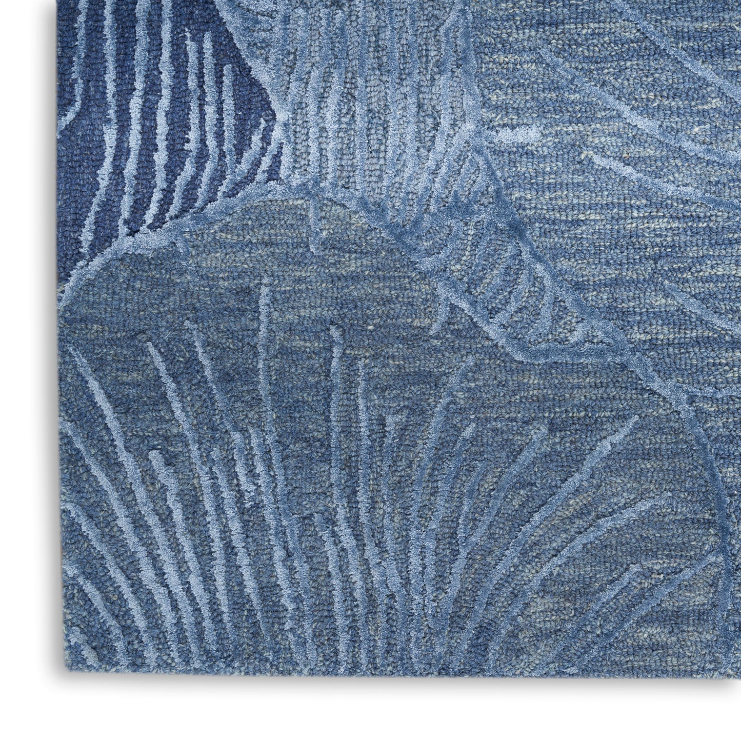 Blue textured rug with abstract leaf-like pattern in lighter blue tones; plush pile.
