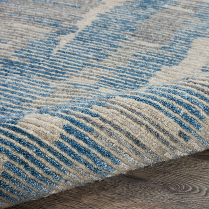 Blue and beige patterned area rug with textured pile on a wooden floor.